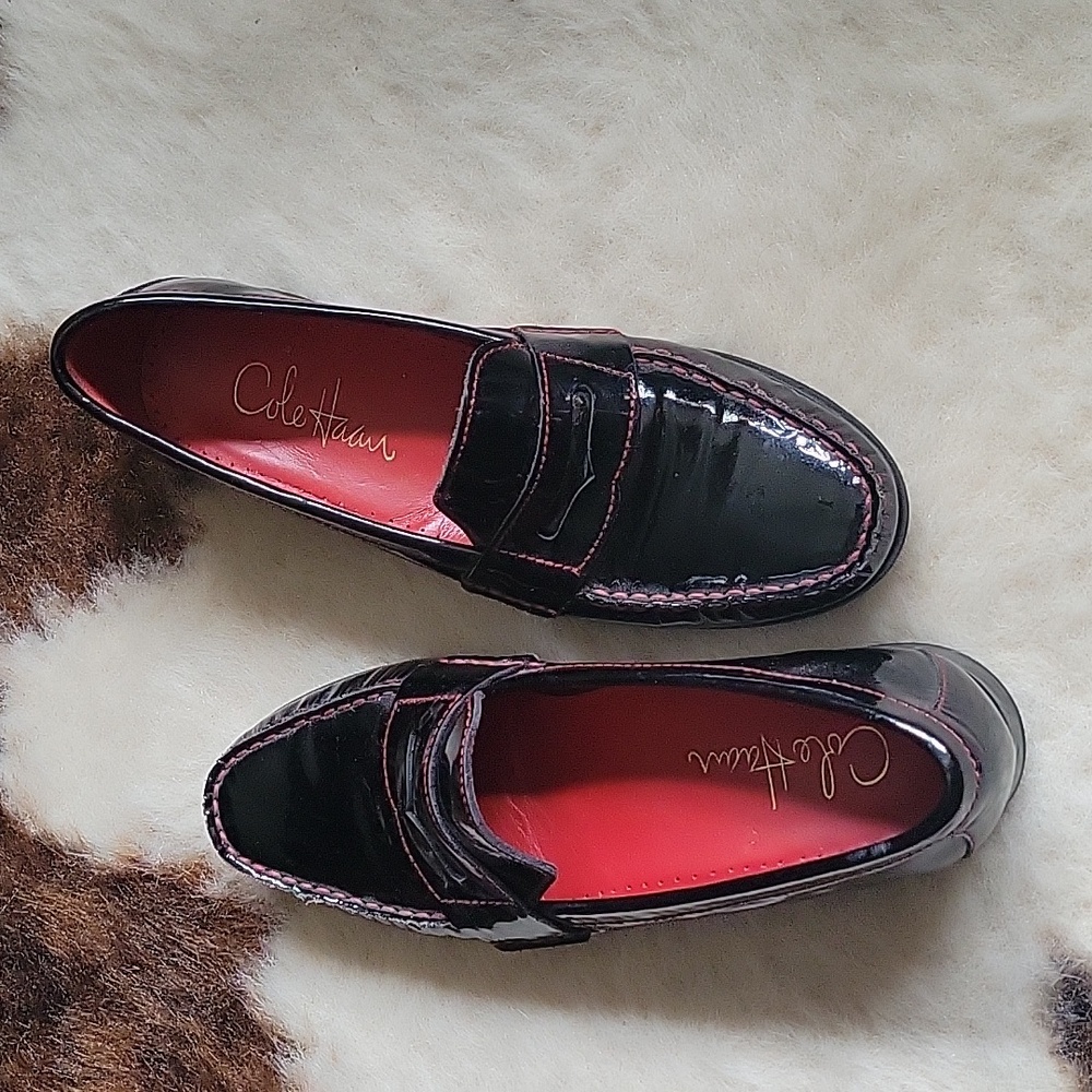 Cole Haan patent leather loafers black with red stitching.